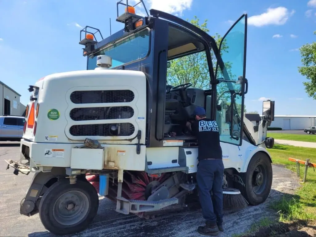 Street sweeper maintenance for improved efficiency under a clear blue sky.