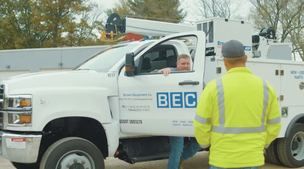 Service truck assisting crew member on site during operation.