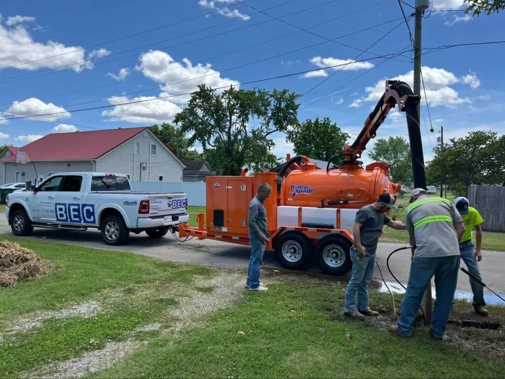 Utility crew operating hydrovac trailer to excavate safely on residential street.