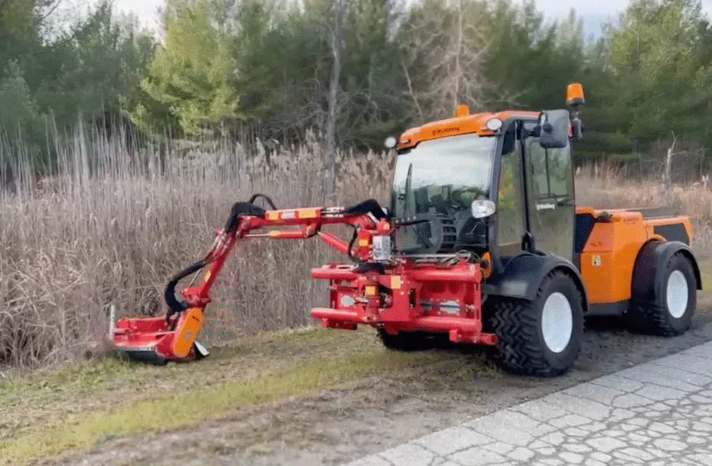 Compact utility tractor with brush cutter efficiently clearing overgrown grass along a pathway.
