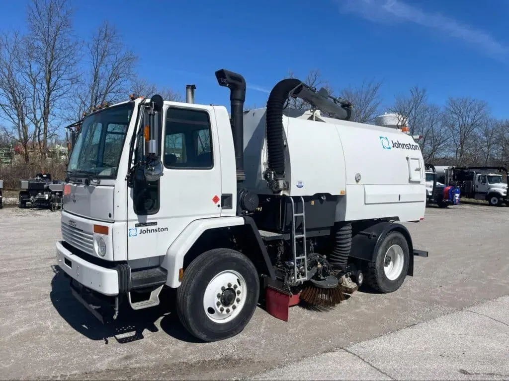 Street sweeper ready for urban cleaning under clear skies.