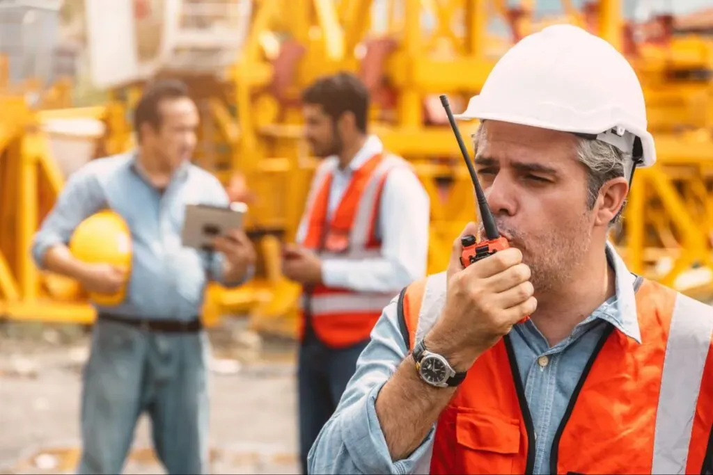 Construction workers using communication devices on-site for effective teamwork and safety.