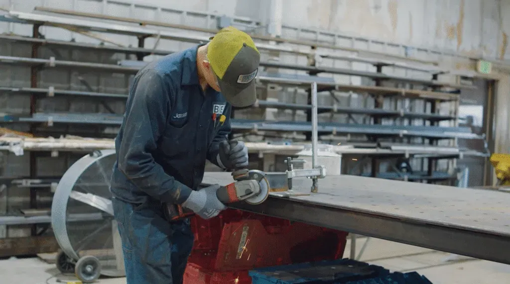 Welder using a grinding tool on metal in a workshop for Equipment Lifecycle Management at Brown Equipment Company