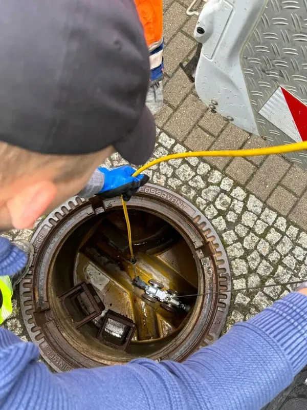 Worker inspecting sewer system with IBAK equipment for efficient drainage maintenance.