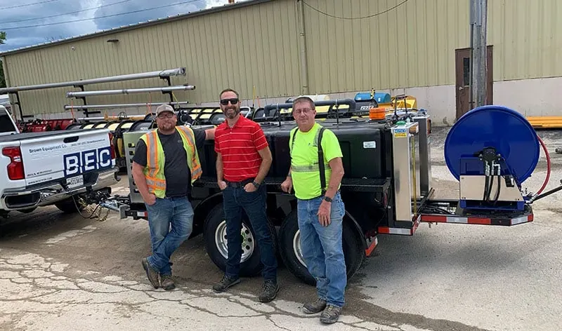 Team of workers posing in front of an industrial. sewer jetter.