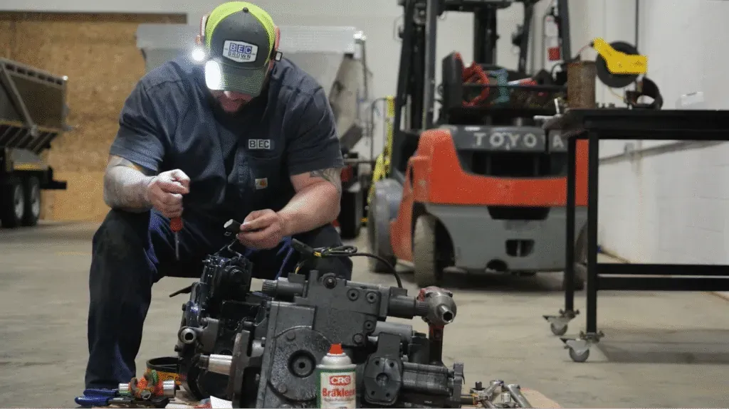 Mechanic repairing heavy machinery engine in a workshop. Tools and equipment visible.