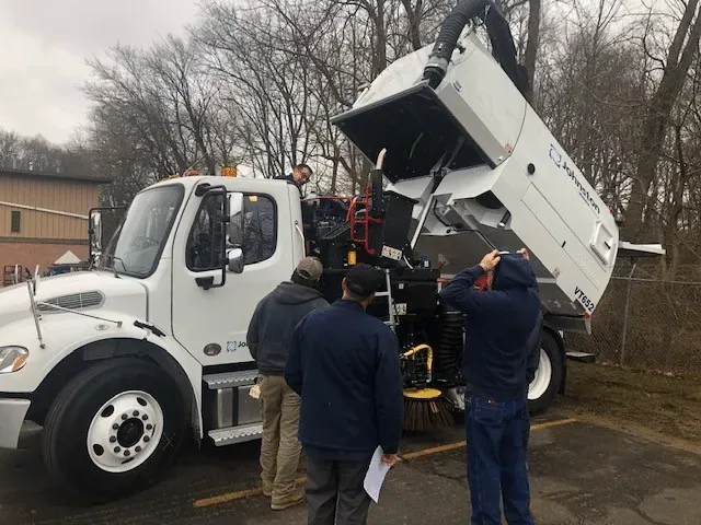 Men reviewing dump truck maintenance procedures in a training session.