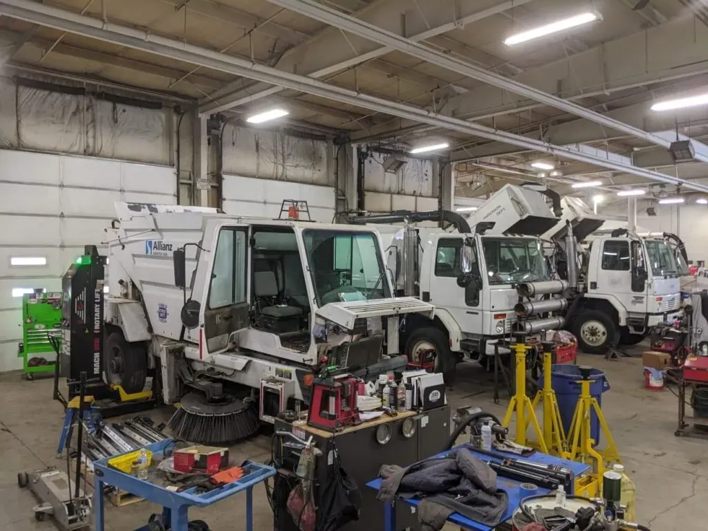 Street sweeper repair garage with maintenance equipment and specialized vehicles for efficient servicing.
