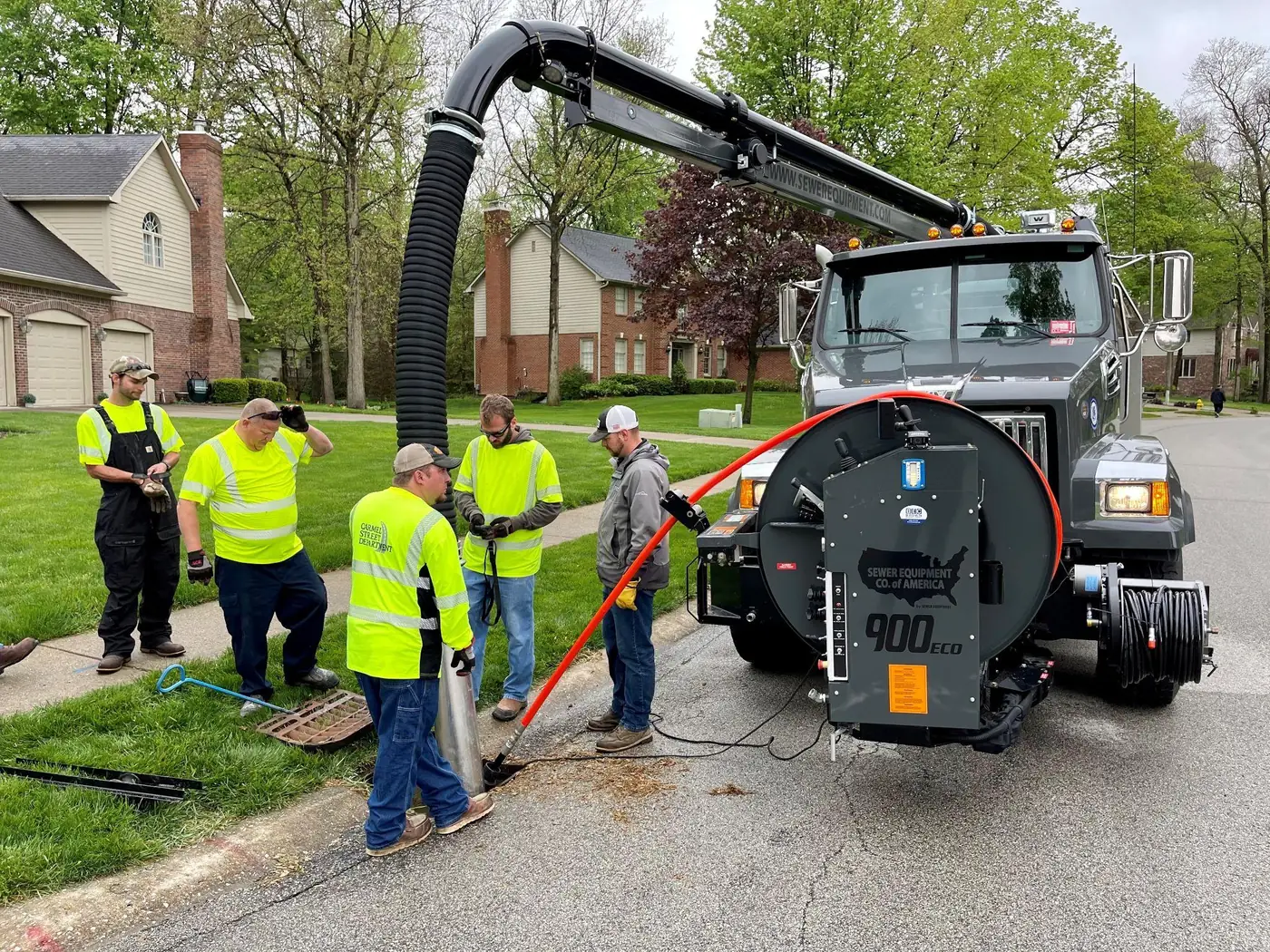 Public works crew gathered at a manhole beside a Sewer Equipment 900 ECO combination sewer truck.