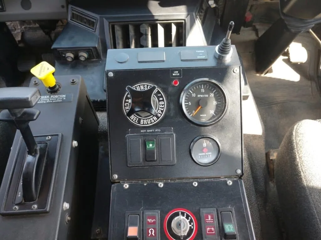 Street sweeper control panel featuring essential gauges and operation switches.