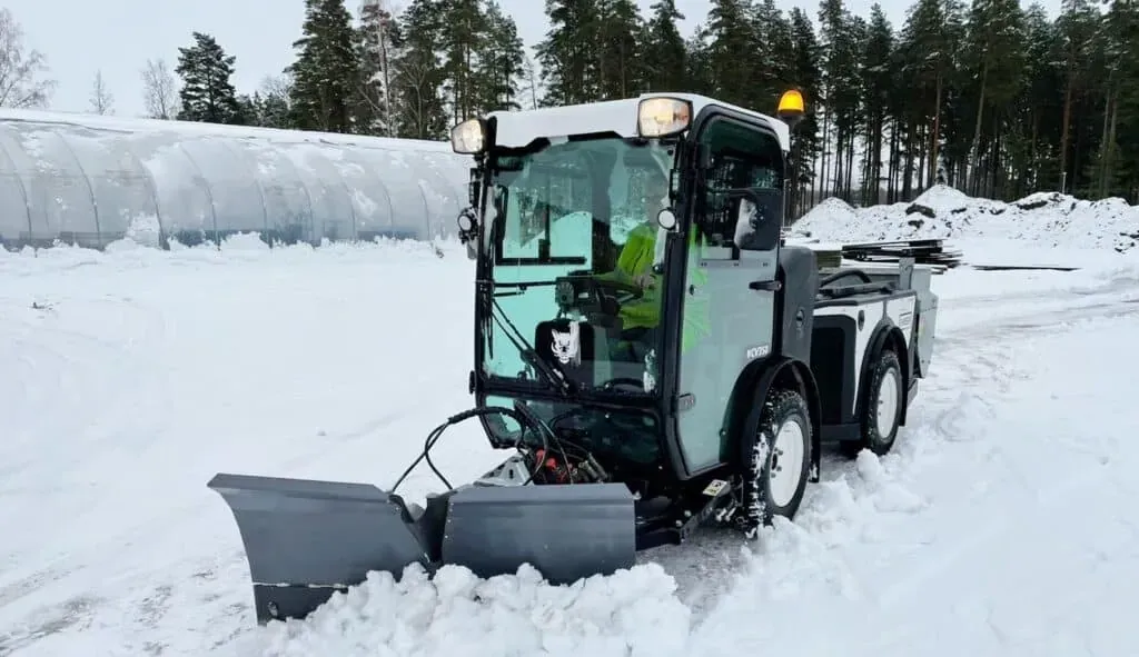 Snow plow vehicle clearing winter roads in a snowy landscape.